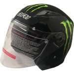 The کلاه کاسکت دی ای وان مدل 402BM is a black motorcycle helmet with a clear visor, bright green Monster Energy claw logos, and white SF1 text on the side. Care and cleaning instructions are printed on the visor.